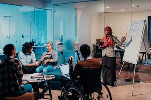 An older Muslim businesswoman presents a project to a young diverse team of people in a modern office photo