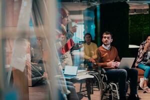 An older Muslim businesswoman presents a project to a young diverse team of people in a modern office photo