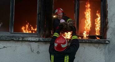 Firefighter hero carrying baby girl out from burning building area from fire incident. Rescue people from dangerous place photo