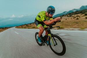 Full length portrait of an active triathlete in sportswear and with a protective helmet riding a bicycle. Selective focus photo