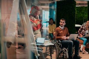 An older Muslim businesswoman presents a project to a young diverse team of people in a modern office photo