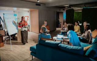 An older Muslim businesswoman presents a project to a young diverse team of people in a modern office photo