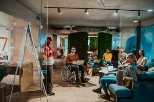 An older Muslim businesswoman presents a project to a young diverse team of people in a modern office photo