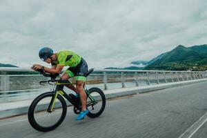 Full length portrait of an active triathlete in sportswear and with a protective helmet riding a bicycle. Selective focus photo