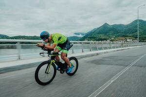 Full length portrait of an active triathlete in sportswear and with a protective helmet riding a bicycle. Selective focus photo