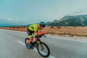 Full length portrait of an active triathlete in sportswear and with a protective helmet riding a bicycle. Selective focus photo