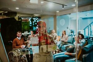 An older Muslim businesswoman presents a project to a young diverse team of people in a modern office photo