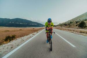 Full length portrait of an active triathlete in sportswear and with a protective helmet riding a bicycle. Selective focus photo