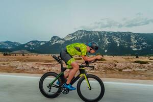 Full length portrait of an active triathlete in sportswear and with a protective helmet riding a bicycle. Selective focus photo