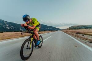 Full length portrait of an active triathlete in sportswear and with a protective helmet riding a bicycle. Selective focus photo