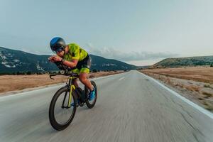 Full length portrait of an active triathlete in sportswear and with a protective helmet riding a bicycle. Selective focus photo