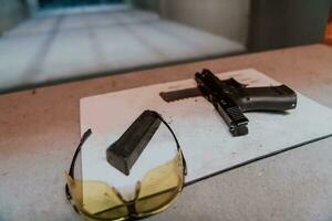 disparo equipo en frente de el objetivo. pistola, gafas de protección y auriculares en el mesa de un moderno disparo rango foto