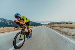 Full length portrait of an active triathlete in sportswear and with a protective helmet riding a bicycle. Selective focus photo