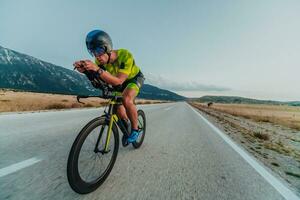 Full length portrait of an active triathlete in sportswear and with a protective helmet riding a bicycle. Selective focus photo