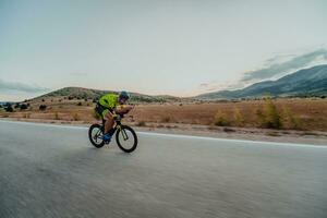 Full length portrait of an active triathlete in sportswear and with a protective helmet riding a bicycle. Selective focus photo