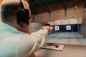 A man practices shooting a pistol in a shooting range while wearing protective headphones photo