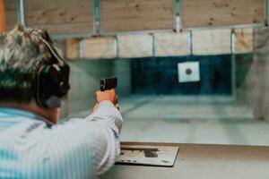 A man practices shooting a pistol in a shooting range while wearing protective headphones photo