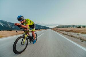 Full length portrait of an active triathlete in sportswear and with a protective helmet riding a bicycle. Selective focus photo