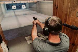 A man practices shooting a pistol in a shooting range while wearing protective headphones photo