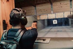 A man practices shooting a pistol in a shooting range while wearing protective headphones photo