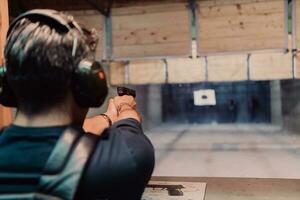 A man practices shooting a pistol in a shooting range while wearing protective headphones photo