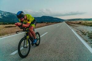 Full length portrait of an active triathlete in sportswear and with a protective helmet riding a bicycle. Selective focus photo