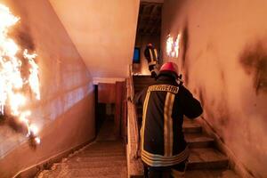 valiente bombero desciende escalera de un ardiente edificio y sostiene salvado niña en su brazos. abierto fuego y uno bombero en el antecedentes. foto