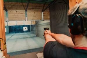 A man practices shooting a pistol in a shooting range while wearing protective headphones photo