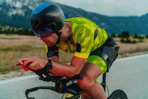 Full length portrait of an active triathlete in sportswear and with a protective helmet riding a bicycle. Selective focus photo