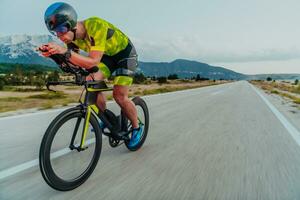 Full length portrait of an active triathlete in sportswear and with a protective helmet riding a bicycle. Selective focus photo