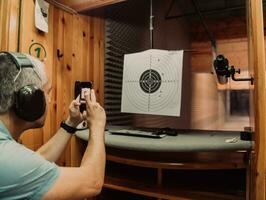 A man in a shooting range takes a picture and examines the results after shooting photo