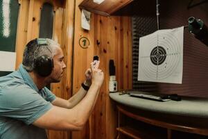 A man in a shooting range takes a picture and examines the results after shooting photo