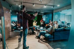 A bearded man in a modern office explaining to his young diverse team how a drone working photo