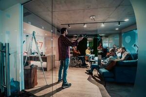 A bearded man in a modern office explaining to his young diverse team how a drone working photo