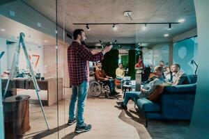 A bearded man in a modern office explaining to his young diverse team how a drone working photo