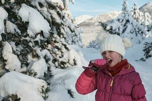 cute little girl  while eating icicle  on beautiful winter day photo