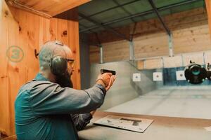 A man practices shooting a pistol in a shooting range while wearing protective headphones photo