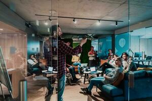 A bearded man in a modern office explaining to his young diverse team how a drone working photo