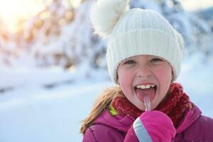 cute little girl  while eating icicle  on beautiful winter day photo