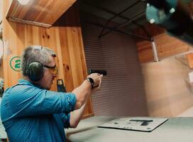 A man practices shooting a pistol in a shooting range while wearing protective headphones photo