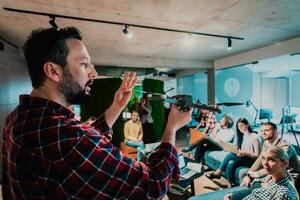 un barbado hombre en un moderno oficina explicando a su joven diverso equipo cómo un zumbido trabajando foto