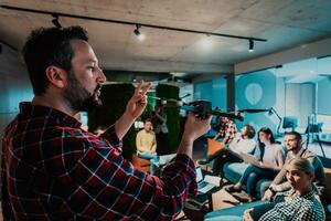 A bearded man in a modern office explaining to his young diverse team how a drone working photo