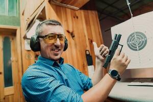 un hombre practicas disparo un pistola en un disparo rango mientras vistiendo protector auriculares foto