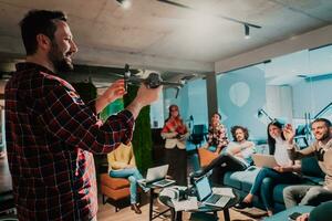 A bearded man in a modern office explaining to his young diverse team how a drone working photo