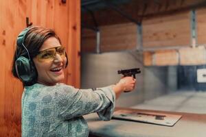 un mujer practicas disparo un pistola en un disparo rango mientras vistiendo protector auriculares foto