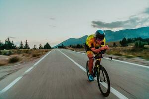 Night drive. Full length portrait of an active triathlete in sportswear and with a protective helmet riding a bicycle in night time.. Selective focus photo