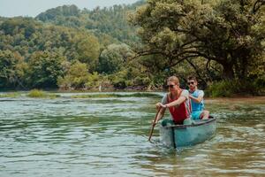 Couple adventurous explorer friends are canoeing in a wild river surrounded by the beautiful nature photo