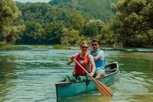 Couple adventurous explorer friends are canoeing in a wild river surrounded by the beautiful nature photo