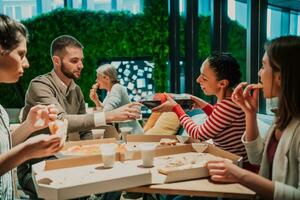 Eating pizza with diverse colleagues in the office, happy multi-ethnic employees having fun together during lunch, enjoying good conversation, and emotions photo