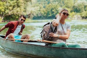 Couple adventurous explorer friends are canoeing in a wild river surrounded by the beautiful nature photo